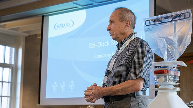 An older man presenting next to a containment system at an Ezi-Dock workshop.
